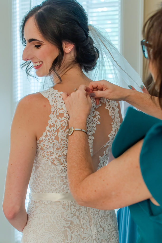 photo of bride's mom buttoning her dress on wedding day
