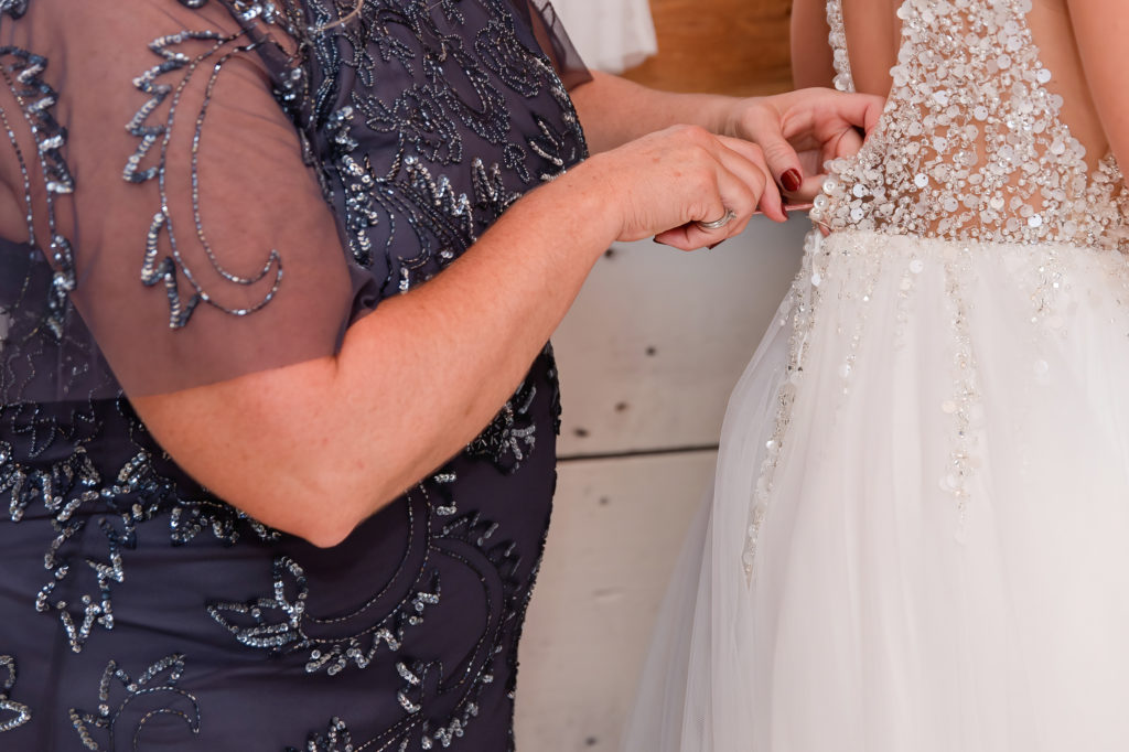 photo of bride's mom zipping up her dress