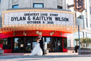 portrait of bride and groom kissing in front of personalized marquee