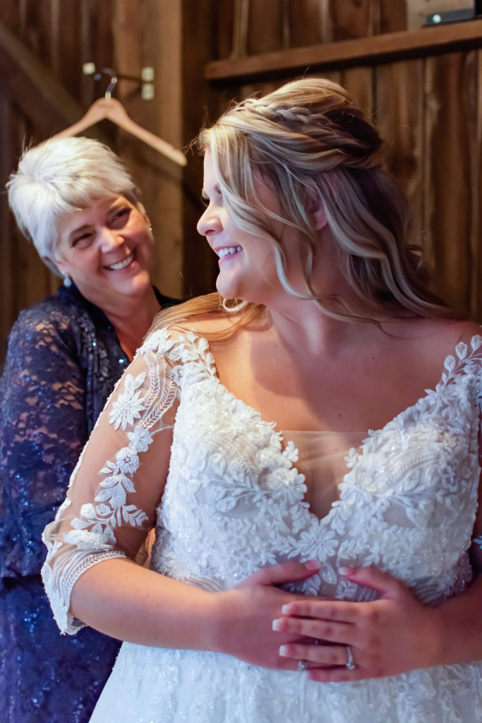 photo of bride's mother helping her put her dress on