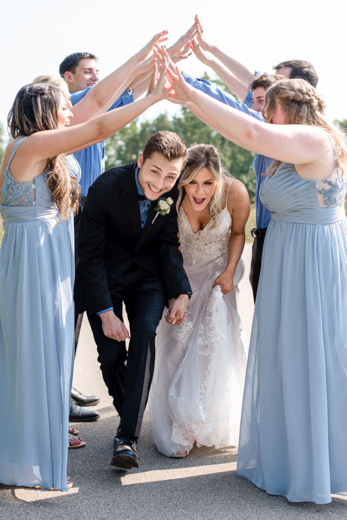 bride and groom run through tunnel made by bridal party on wedding day