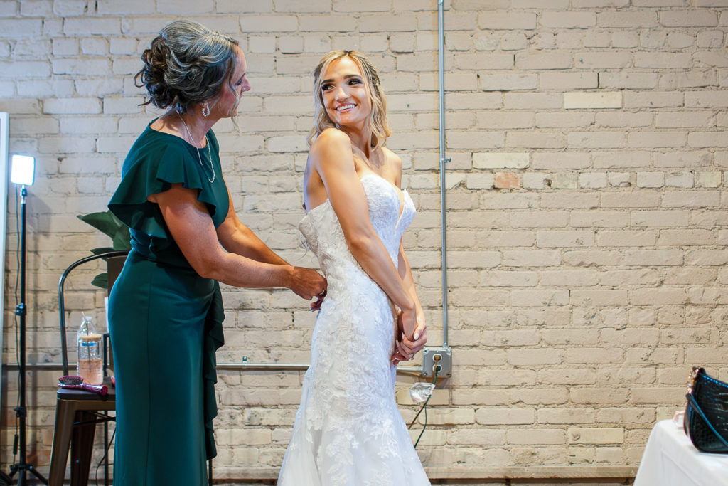 photo of bride's mom zipping up her wedding dress