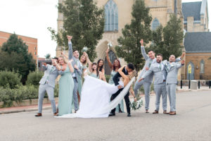 photo of bride and groom kissing while bridal party celebrates