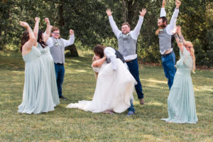 photo of groom dipping and kissing bride while bridal party cheers