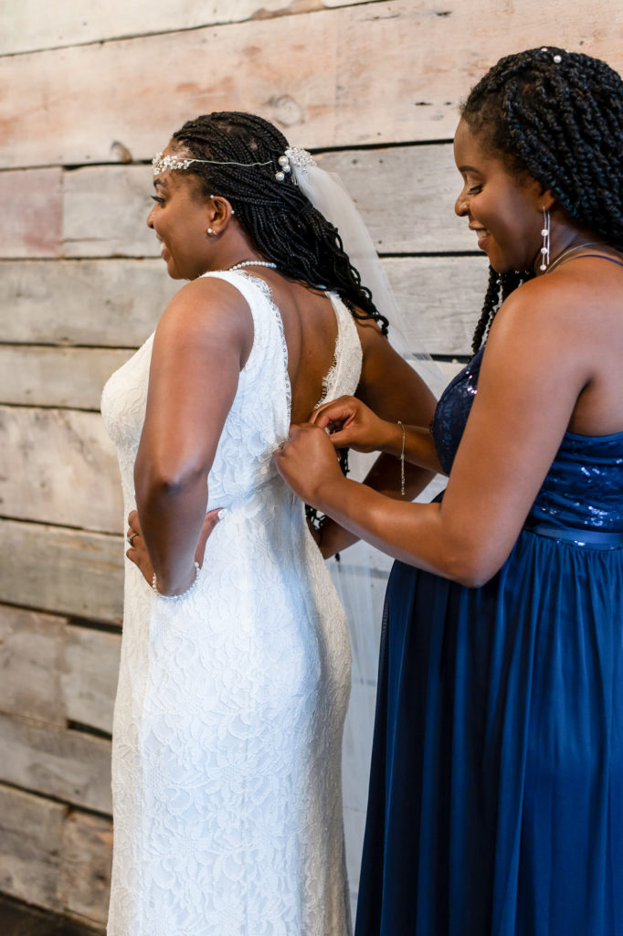 maid of honor zipping up bride's dress on wedding day