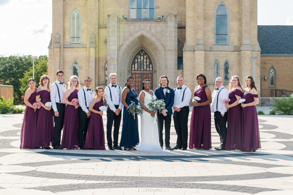 wedding bridal party posing in front of cathedral
