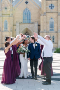 bride and groom walking through wedding party during portraits