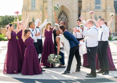 bride and groom kissing while wedding party cheers