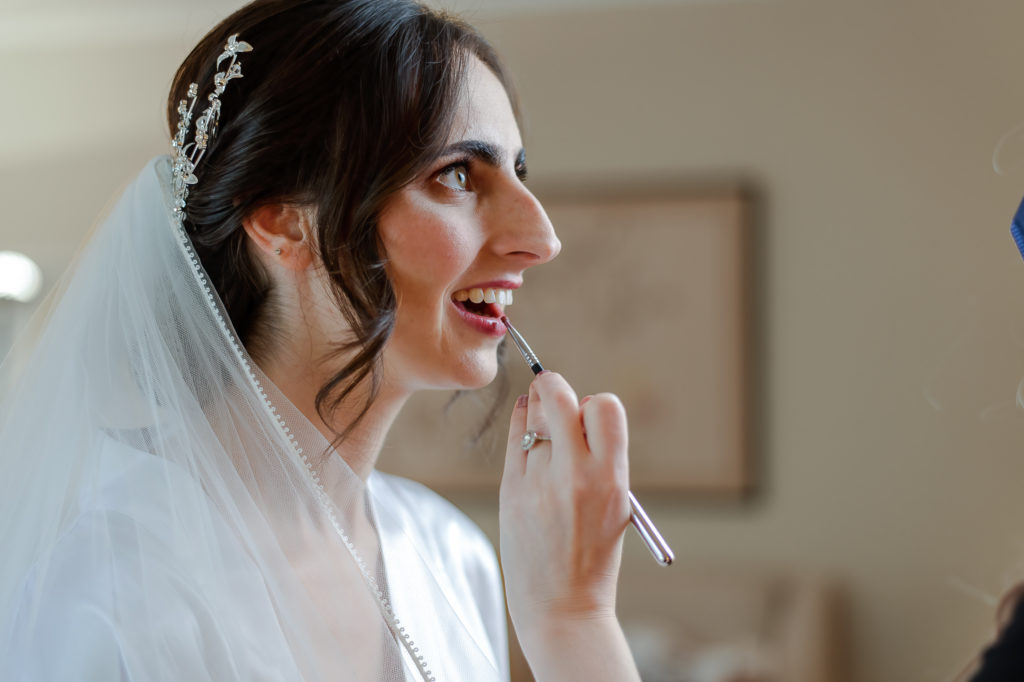 photo of bride getting makeup done on wedding day