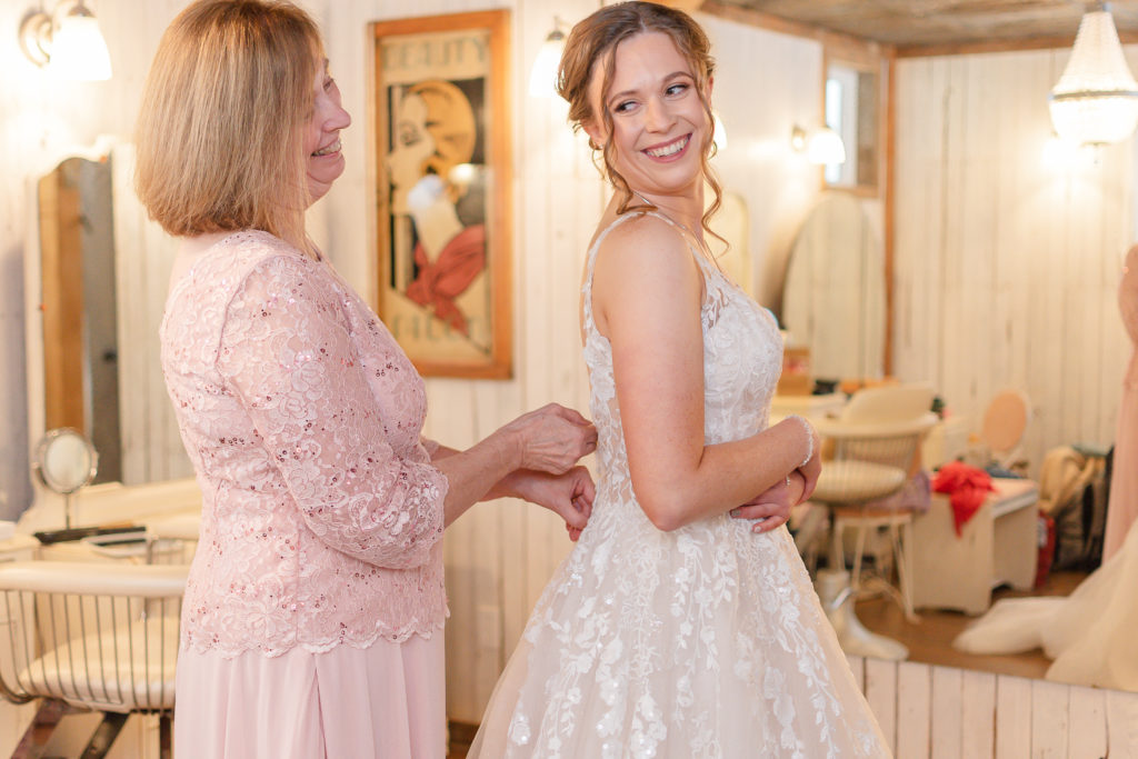 photo of bride's mom helping her zip up dress