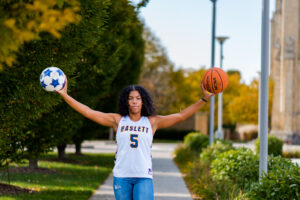 photo of senior holding a soccer and basketball during senior session